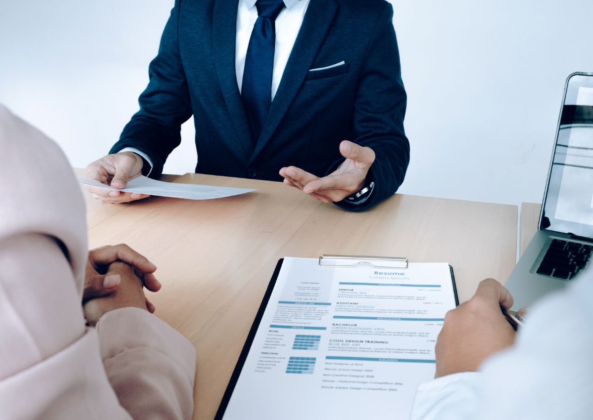 Un recruteur examine un CV papier et un ordinateur portable, potentiellement pour un CV en ligne.