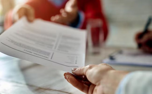 Une main tend un CV papier, symbolisant l'échange d'informations pour un possible CV en ligne.